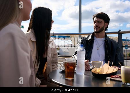 Friends talking and enjoying drinks in outdoor cafe Stock Photo