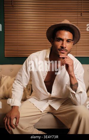 Confident man wearing fedora hat and open white shirt posing Stock Photo