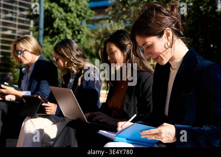 Businesswomen collaborating outdoors using modern technology Stock Photo
