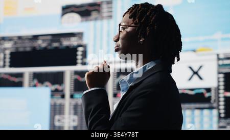 Management executive comparing company metrics on digital videowall before making decisions. Entrepreneur analyzing key performance indicators to optimize startup profitability, camera B Stock Photo