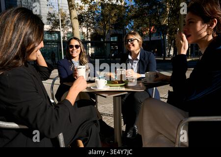 Business women friends having coffee break laughing outdoors Stock Photo