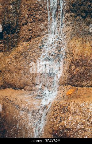 Closeup of water flowing over textured rock surface creating natural abstract pattern and motion, Minimal cascade detail with wet stone and dynamic Stock Photo