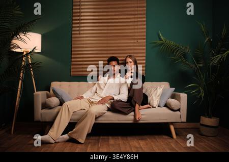 Young diverse couple relaxing together on sofa Stock Photo