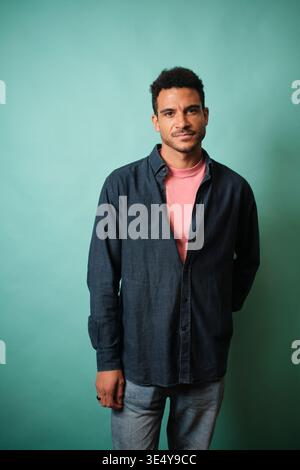 Confident young man standing against teal background Stock Photo