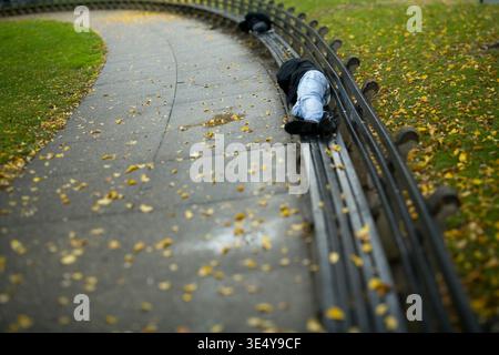 Homeless man sleeping on an empty park bench. Stock Photo