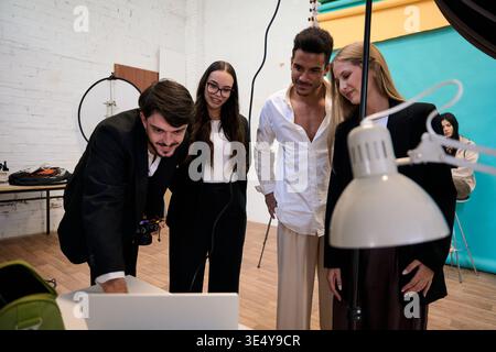 Creative team collaborating viewing results on laptop in studio Stock Photo