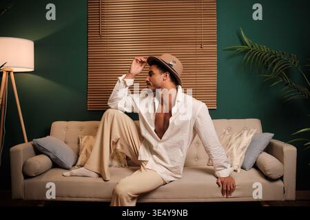 Stylish man in fedora relaxing on sofa Stock Photo