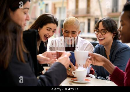 Diverse friends enjoying coffee sharing laughter at cafe Stock Photo