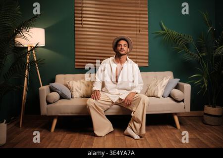 Confident man posing sitting on a stylish couch Stock Photo