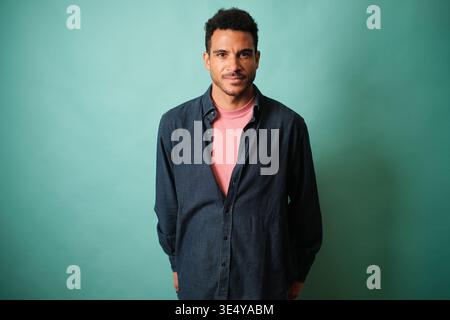 Confident young man posing against teal background Stock Photo