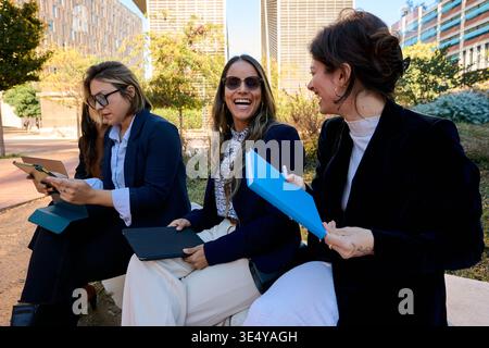 Businesswomen team collaborating and laughing during outdoor meeting Stock Photo