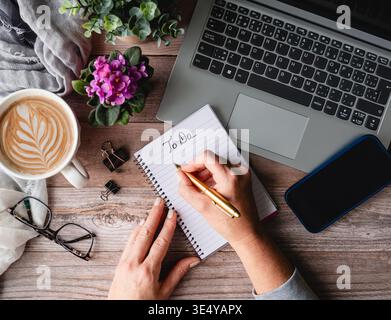 Top view hands writing on notepad near computer, phone on desk. Stock Photo