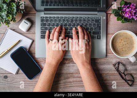 Top view hands typing on computer on desk with phone,coffee. Stock Photo