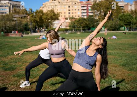 Women practicing outdoor yoga in a green park Stock Photo