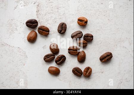 Top view of whole roasted coffee beans on light stone background. Stock Photo