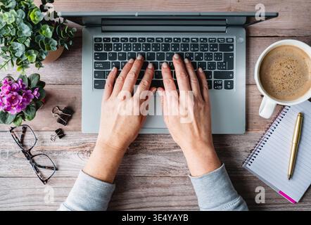 Top view hands typing on laptop computer on desk with coffee. Stock Photo