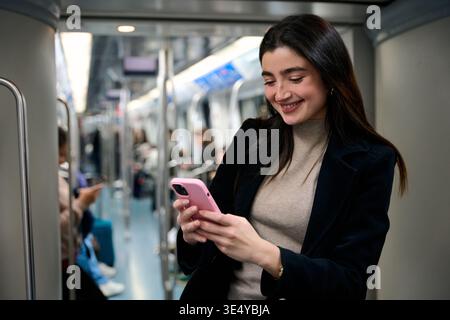 Young woman smiling using phone commuting on subway train Stock Photo