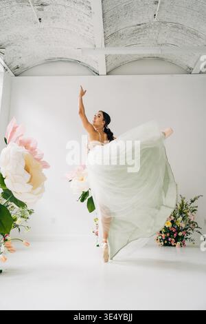 Ballet dancer dancing with flowing skirt in bright floral studio Stock Photo