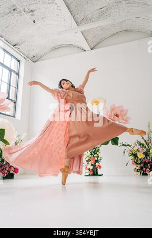 Ballerina performing ballet pose surrounded by floral decorations Stock Photo