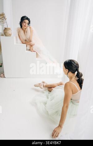 Two ballerinas sitting in minimalist studio space Stock Photo