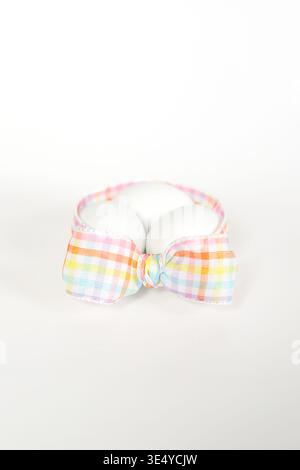 Three white eggs artfully arranged inside a loop of plaid ribbon Stock Photo