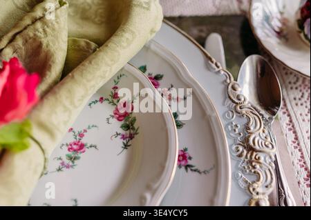 Close-up of vintage floral china with ornate silverware and napkin Stock Photo