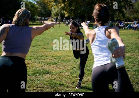 Three women practicing yoga in park balancing dancer pose Stock Photo