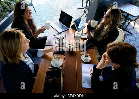 Businesswomen meeting collaboratively outdoors drinking coffee and smiling Stock Photo