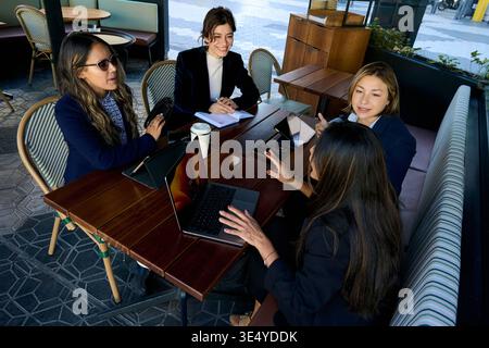 Businesswomen meeting at cafe collaborating on project work Stock Photo