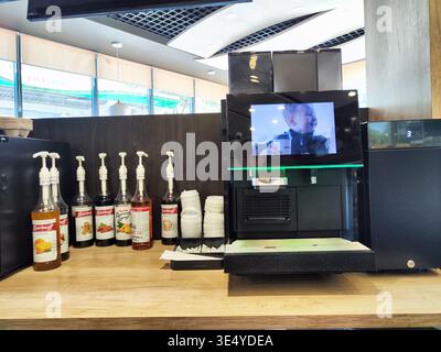 Yelabuga, Russia - June 15, 2024: A coffee machine is displayed next to various syrup dispensers in a cafe. The setting is bright with customers in th Stock Photo