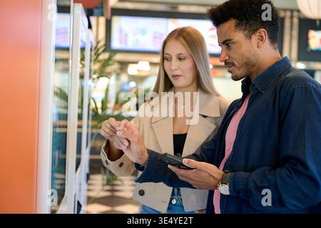 Couple using touch screen kiosk for ordering food Stock Photo