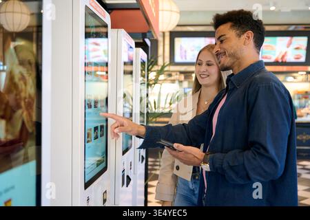 Couple using self service kiosk for fast food order Stock Photo