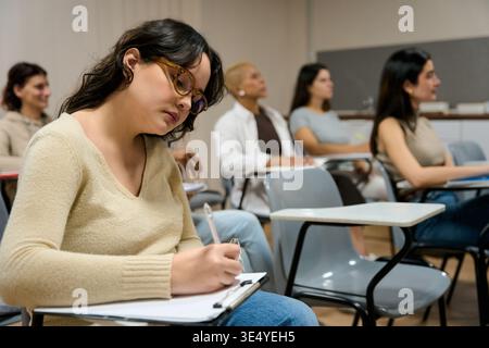Female student writing notes during university lecture Stock Photo