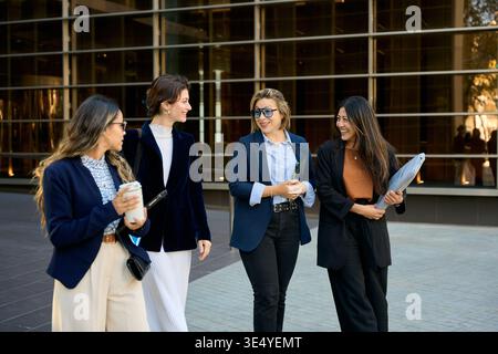 Diverse businesswomen walking and talking outdoors in city Stock Photo