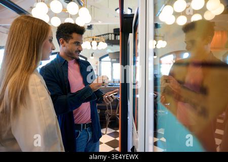 Couple using self service kiosk for ordering food Stock Photo