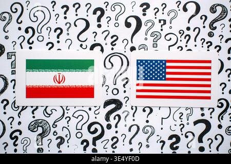 IRAN and USA flags rest on background filled with hand drawn question marks. US-Iran relations, geopolitical tension, international sanctions Stock Photo