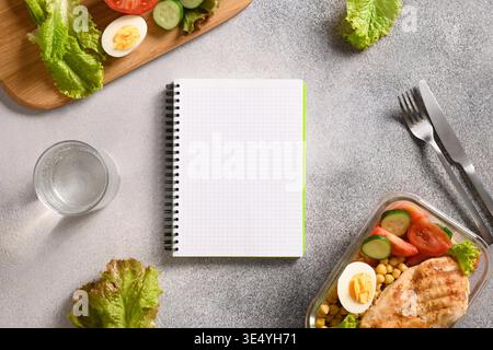 Weight loss concept, calories counting, diet, food control and calorie counter, diet plan. Notebook, food, salad, egg , water and vegetable on gray background. Top view. Copy space. Stock Photo