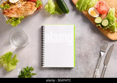Weight loss concept, calories counting, diet, food control and calorie counter, diet plan. Notebook, food, salad, egg , water and vegetable on gray background. Top view. Copy space. Healthy eating concept. Stock Photo