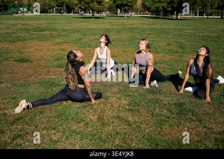 Women doing yoga stretching exercise outdoors in park Stock Photo