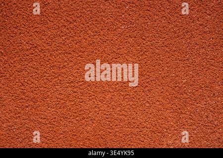 Close up of a bright red stucco wall with fine rough texture. Minimal abstract background with uniform grain and vibrant solid color. Stock Photo