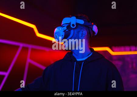 handsome man using virtual reality headset with neon light. VR, future, gadgets, technology, education online, studying, video game concept Stock Photo