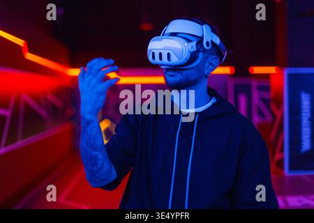 Handsome cool young man in glasses of virtual reality on dark background with neon light. VR glasses. Augmented and virtual reality Stock Photo