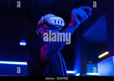 young man engages with a virtual world using a mixed reality spacial computer headset, symbolizing cutting-edge technology in gaming and immersive dig Stock Photo