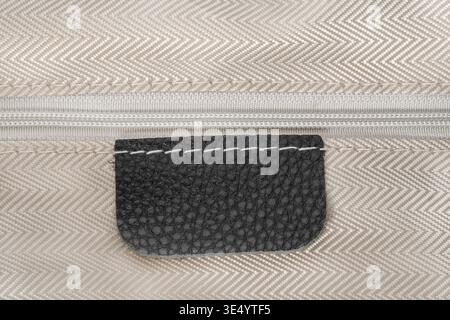 Blank black leather patch stitched on beige zipped fabric background Stock Photo