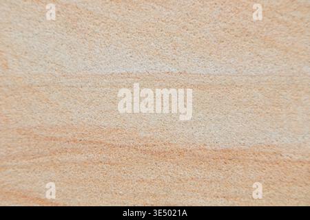 Macro detail of a smooth-textured sandstone surface showing subtle horizontal banding and tonal gradation from pale cream to warm peach. Stock Photo