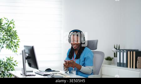 Medical professional using smartphone and headset at office desk Stock Photo