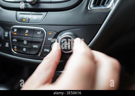 The hand regulates the temperature in the car interior. Air conditioner control Stock Photo