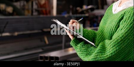 Close-up of inspector documenting inventory with steel profiles in background Stock Photo