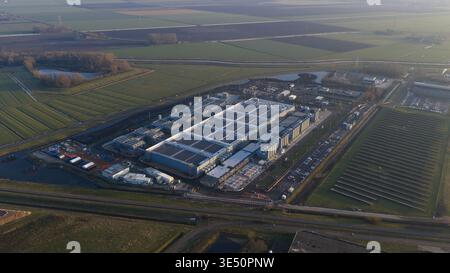 Aerial view of Datacenter Winschoten featuring massive industrial halls, cooling units, and solar panels surrounded by green agricultural fields in Wi Stock Photo