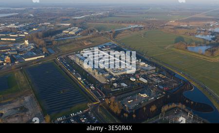 Aerial view of the Datacenter Winschoten facility featuring extensive solar panel arrays and industrial cooling systems surrounded by green fields and Stock Photo